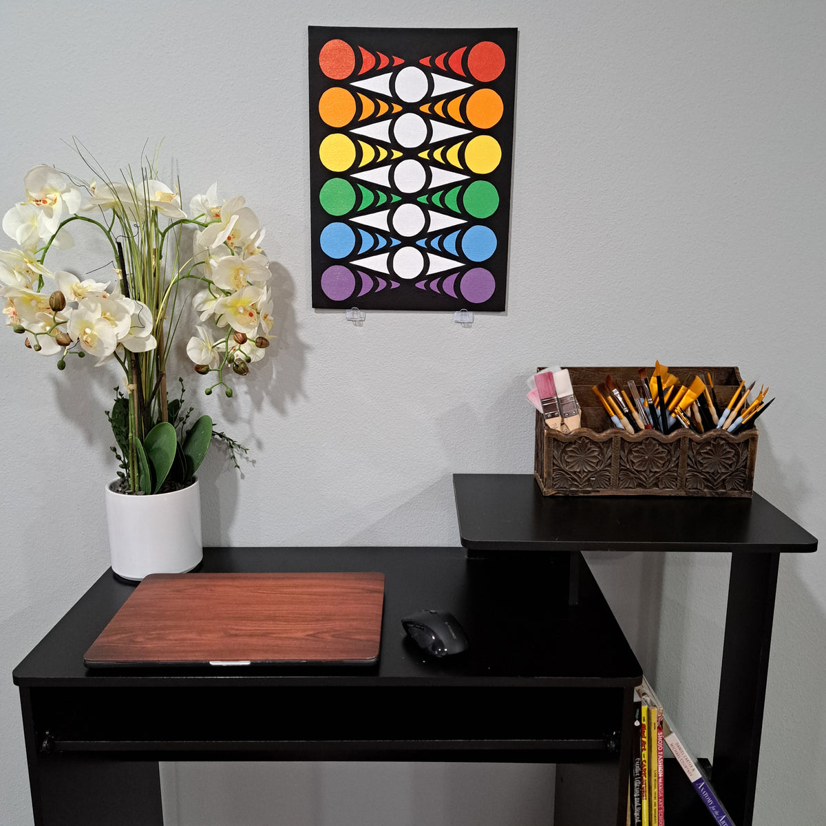 Staged photo of the "Eye Chevron" painting hung up on the wall behind a desk