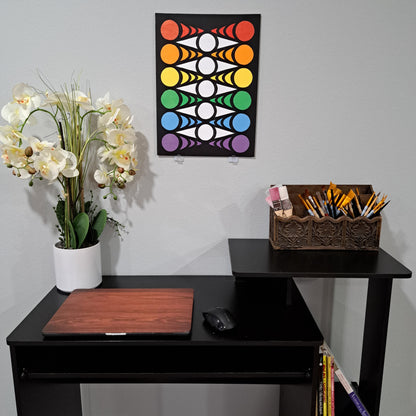 Staged photo of the "Eye Chevron" painting hung up on the wall behind a desk