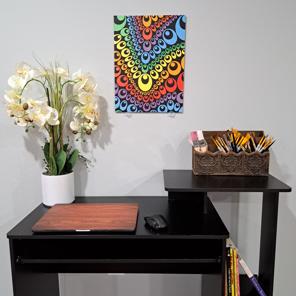 Staged photo of the "Rows of Teardrops: painting hanging on a wall behind a desk