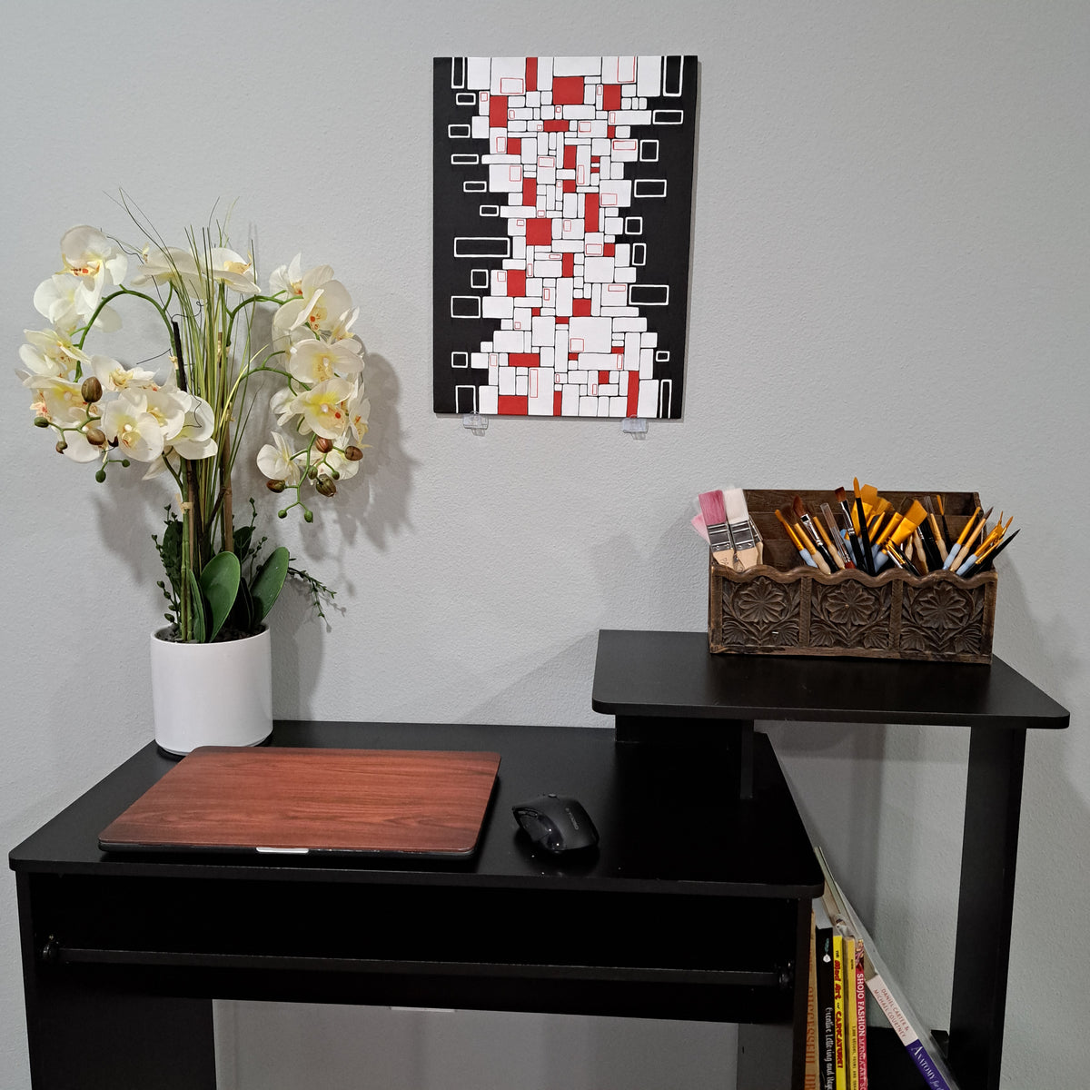 Staged photo of the "Tower of Tiles" painting hung up on the wall behind a desk